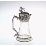 A SILVER PLATE AND ETCHED GLASS CLARET JUG Having a rampant lion finial, embossed decoration and