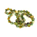 A CARVED HARD STONE BEAD NECKLACE The single strand of spherical green and purple beads. (approx