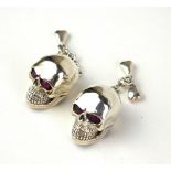 A PAIR OF SILVER 'SKULL' GENT'S CUFFLINKS Each set with red glass eyes, marked 'Sterling'.