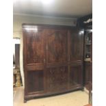 AN EARLY 20TH CENTURY FLAME MAHOGANY TRIPLE WARDROBE Wth scroll carved cornice above three cupboards
