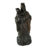 AN EARLY 20TH CENTURY CHINESE ROSEWOOD GROUP CARVING OF IMMORTAL FIGURE HOLDING A CHILD Raised on