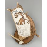 A 20TH CENTURY FALLOW DEER ANTLER CARVING OF ST HUBERTUS UPON A HARDWOOD WALL PLAQUE (h 42cm x w