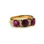 AN 18CT GOLD, RUBY AND DIAMOND RING Having a row of three oval cut rubies interspersed with round