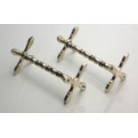 A PAIR OF SILVER KNIFE RESTS Having 'X' frame ends and shaped columns, hallmarked Birmingham,