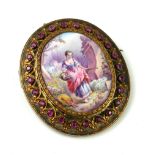 A VINTAGE SILVER GILT, RUBY AND ENAMEL ON COPPER BROOCH The oval central panel hand painted with a