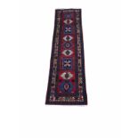 A MIDDLE EASTERN WOOLEN TRIBAL RUNNER The central lozenges on a red ground. (295cm x 80cm)