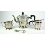 AN ART DECO THREE PIECE SILVER TEA SERVICE Stepped geometric form with carved wooden handle,