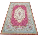 AUBUSSON, A WOOLLEN RUG OF CARPET PROPORTIONS With floral central field on a puce ground contained