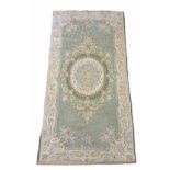 AN AUBUSSON WOOLLEN RUG Hand woven with floral decoration on pale green ground. (approx 77cm x