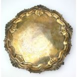 AN EDWARDIAN SILVER SALVER TRAY Having scroll and shell border, on tripod legs and eagle claw