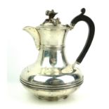 A VICTORIAN SILVER HOT WATER JUG Having a floral finial and ebonised handle, J.W. Benson, London,