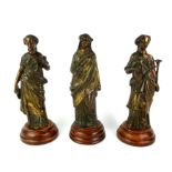 A SET OF THREE BRONZED CLASSICAL FEMALE FIGURES Holding a trumpet, scroll and oil lamp, on a