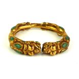 A CHINESE YELLOW METAL AND TURQUOISE BANGLE Modelled with opposing dragons set with cabochon cut