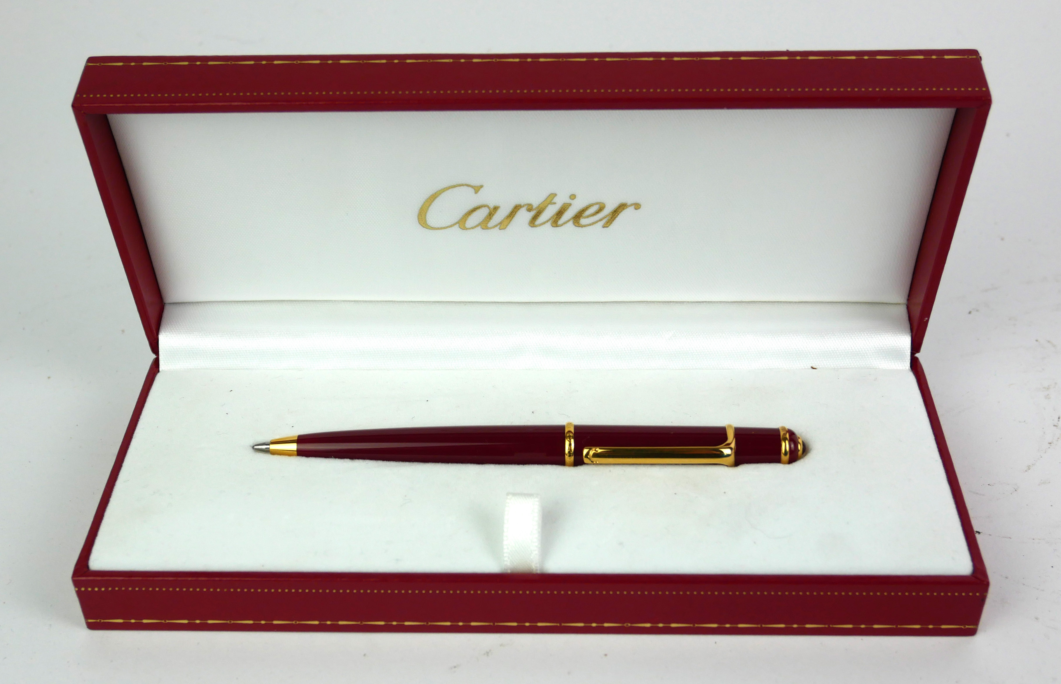 CARTIER, A VINTAGE BALLPOINT PEN Rouge case with gold plated clip, in a fitted Cartier box. (