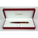 CARTIER, A VINTAGE BALLPOINT PEN Rouge case with gold plated clip, in a fitted Cartier box. (