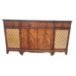 A REGENCY STYLE MAHOGANY BREAKFRONT SIDE CABINET With three drawers above enclosed and brass grilled