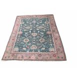 A TURKISH WOOLEN RUG OF CARPET PROPORTIONS The central floral field on a green and pink ground