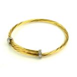 AN 18CT BICOLOUR GOLD AND DIAMOND BANGLE Having a rope twist design with white metal and diamond set