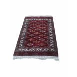 A TURKMAN WOOLEN RUG The central field on a wine red ground contained within running borders. (247cm