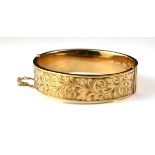 A VINTAGE 9CT GOLD OVAL BANGLE With engraved scrolled decoration. (approx 6cm)