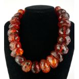 A LARGE VICTORIAN AMBER NECKLACE Having a single row of carved faceted oval beads. (each bead approx