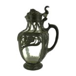 A CONTINENTAL ART NOUVEAU PEWTER AND GLASS CLARET JUG The lid set with a mask of bacchus with grapes