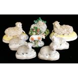 STAFFORDSHIRE, A PAIR OF MODELS OF SEATED SHEEP Painted in yellow glazes and gilt, raised on oval