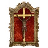 AN 18TH CENTURY CONTINENTAL CARVED WOOD CRUCIFIX SET INTO A BAROQUE CARVED GILTWOOD FRAME