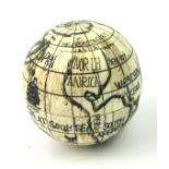 A 20TH CENTURY CARVED BONE SPHERICAL POCKET GLOBE COMPASS With black ink decoration and a glazed