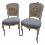 A PAIR OF FRENCH GREY PAINTED CHAIRS With caned backs and overstuffed upholstered seats, on cabriole