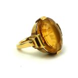 AN ART DECO YELLOW METAL AND CITRINE RING The oval cut citrine set in a geometric stepped design