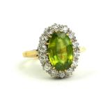A YELLOW METAL, PERIDOT AND DIAMOND RING The oval cut central peridot edged with round cut diamond