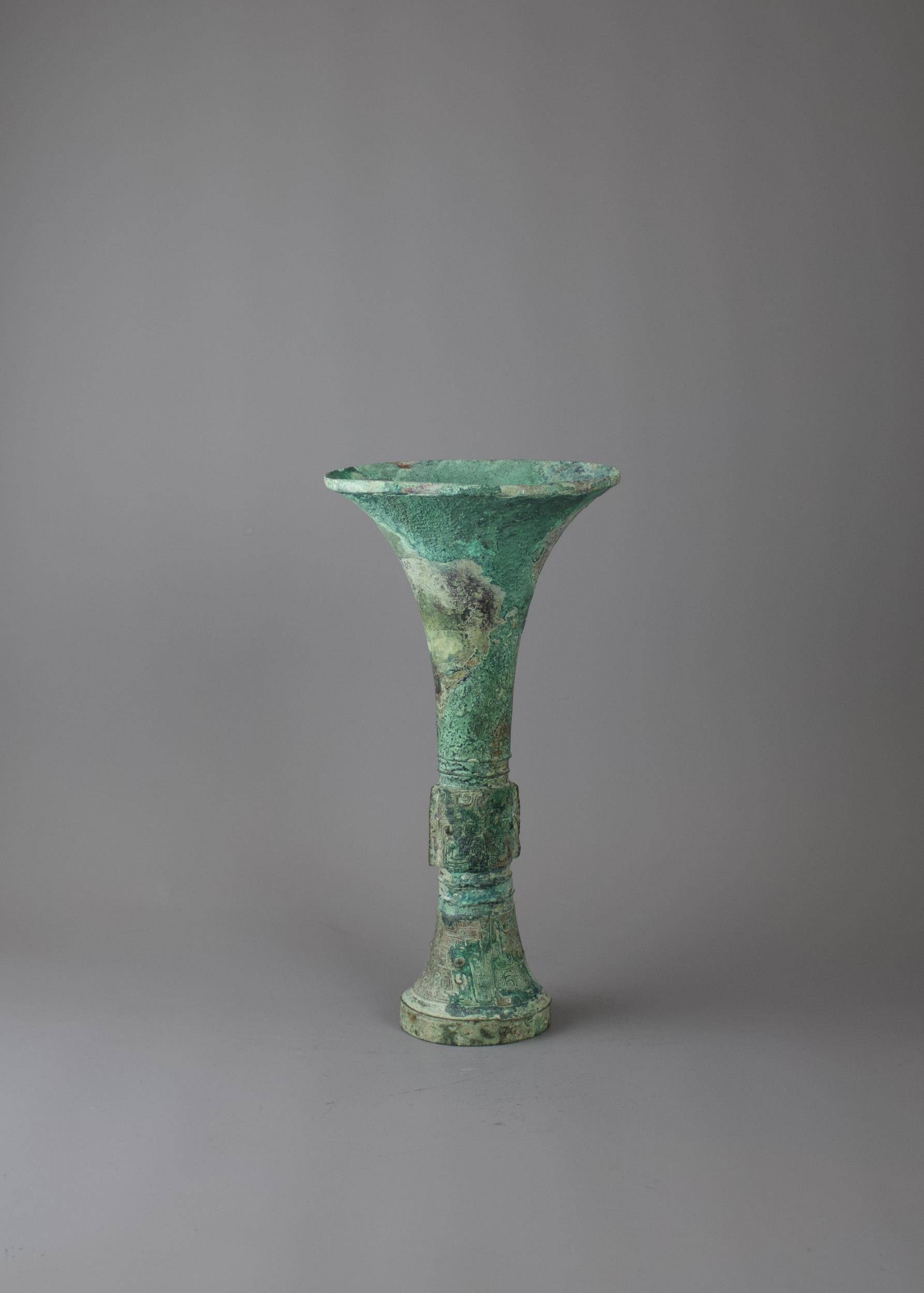 A bronze gu beaker vase, with bands of Taotie masks in low relief on the central bulb and above
