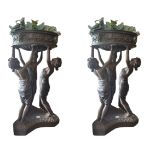 A PAIR OF BRONZE PLANTERS, the circular bowls cast with lion masks and vines being held aloft by