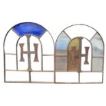 A PAIR OF VINTAGE STAINED GLASS ARCHED WINDOWS With iron lettering. (w 82cm x h 100cm)