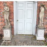 A MATCHED PAIR OF LARGE RECONSTITUTED STONE STATUES SEMI CLAD MAIDENS, on square plinth bases.