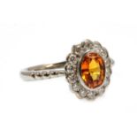 An 18ct white gold orange sapphire and diamond oval cluster ring,