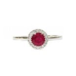 A white gold ruby and diamond halo cluster ring,