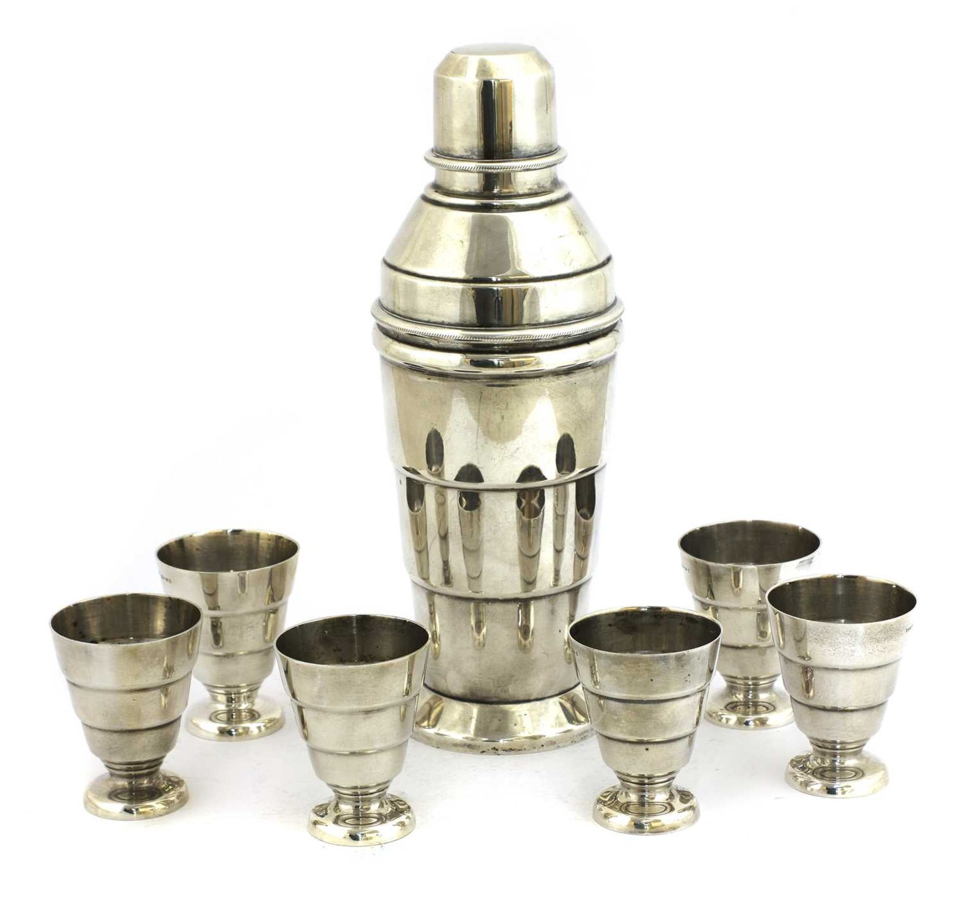 An Art Deco silver-plated cocktail shaker and six beakers,