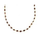 A gold garnet rivière necklace,