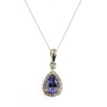 A white gold tanzanite and diamond halo cluster pendant,