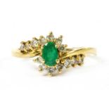 An 18ct gold emerald and diamond crossover cluster ring,