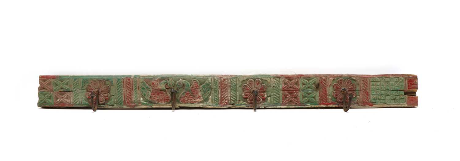 An Indian carved wood and polychrome decorated rack of four coat hooks,