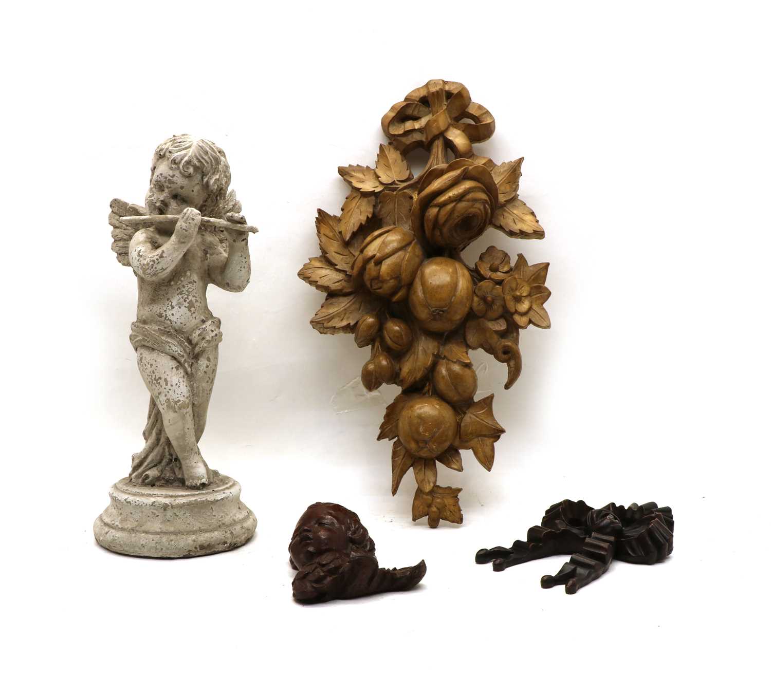 A carved and painted wooden figure of a cherub playing a flute,