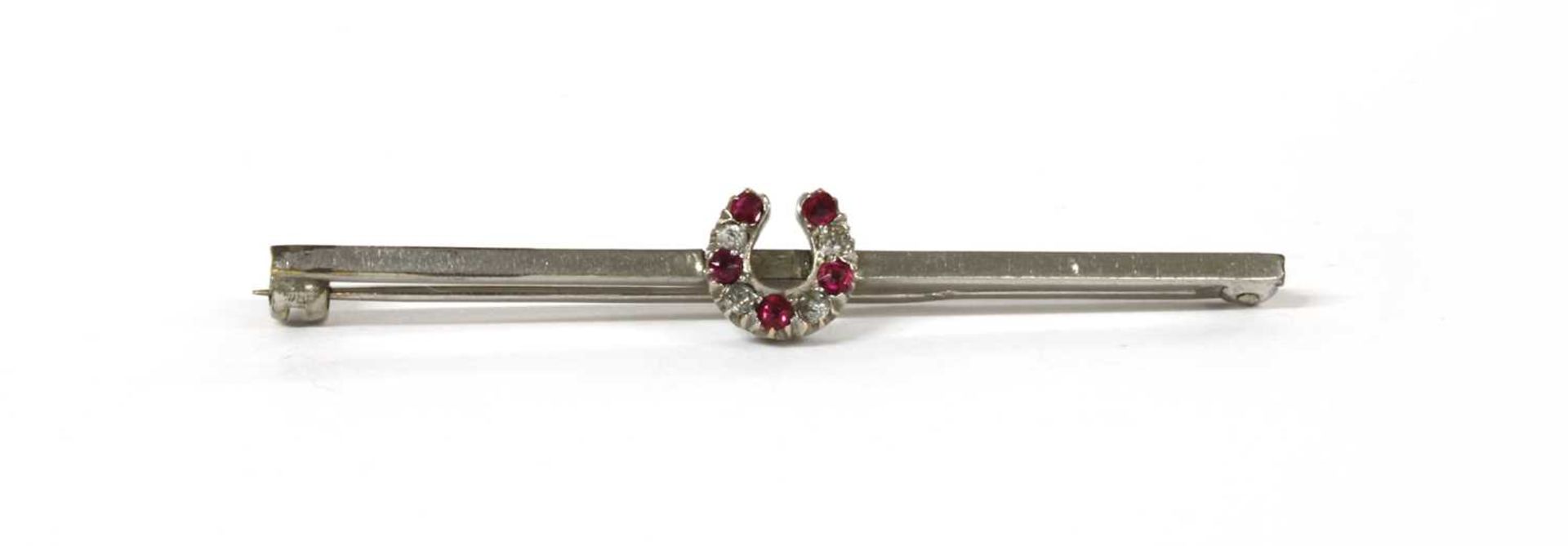 A white gold ruby and diamond horseshoe bar brooch,