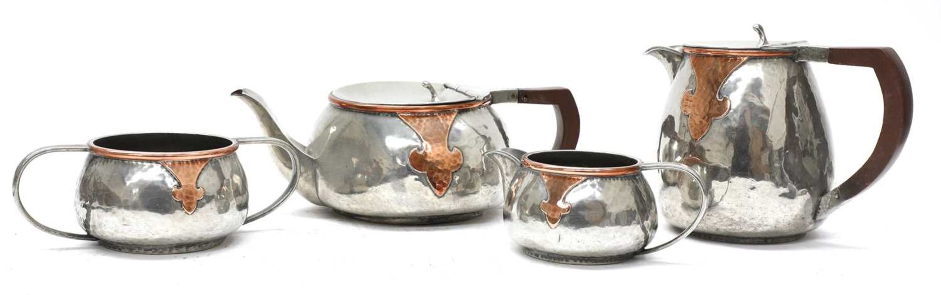 An Arts and Crafts pewter and copper mounted four-piece tea set,