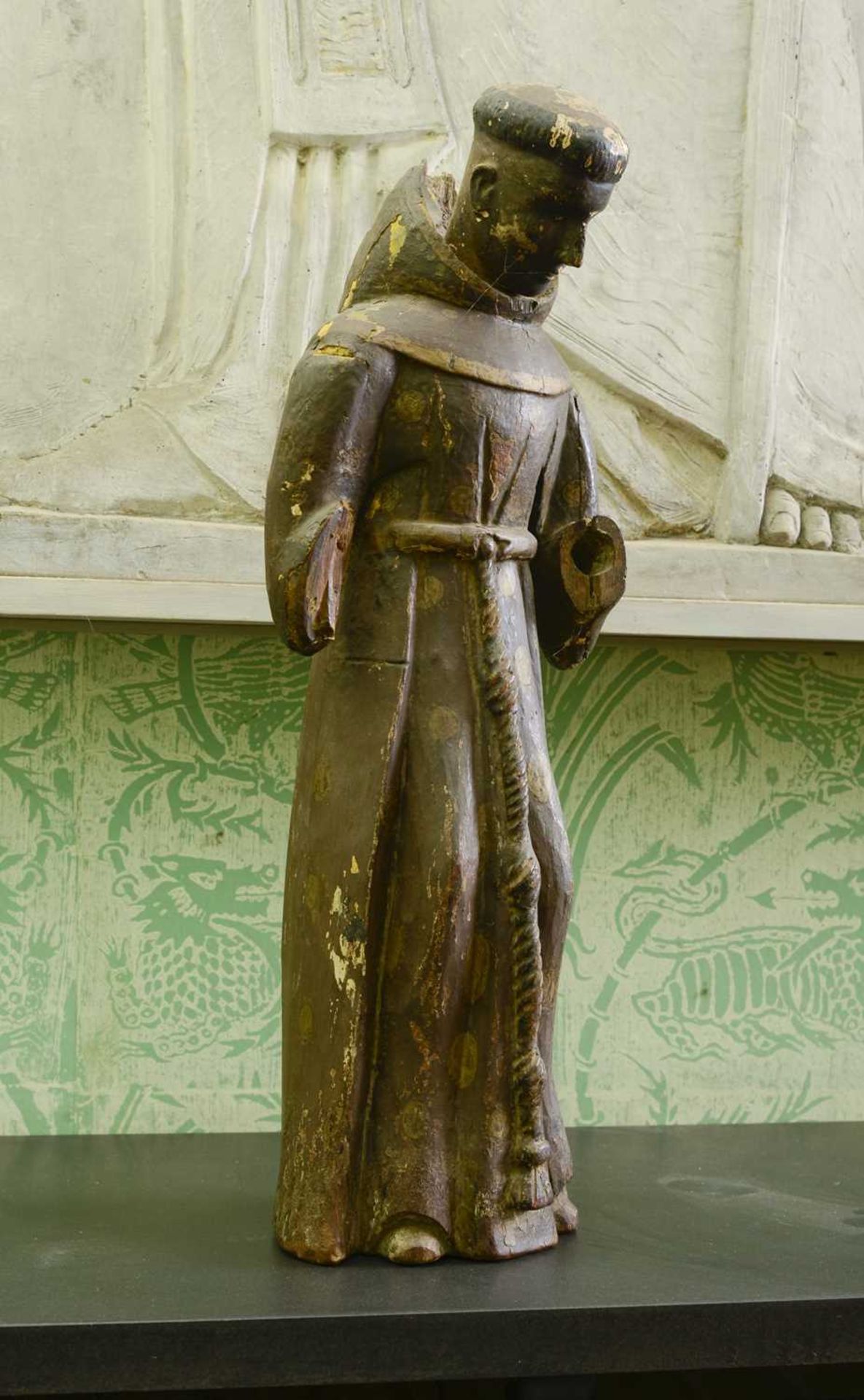 A carved wooden and painted figure of a monk,