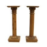 A pair of polished pine torcheres,