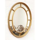 A George III-style oval wall mirror with mirrored slip,