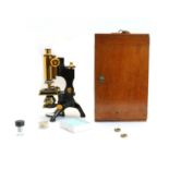 A black and lacquered compound brass monocular microscope,